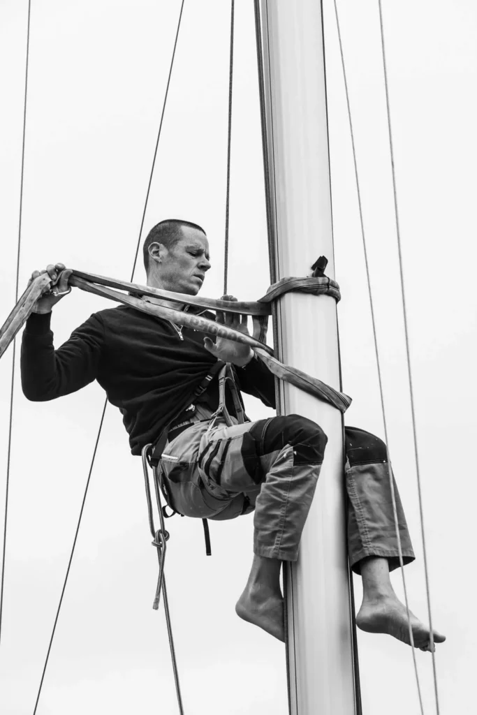 Un technicien de Reboat grimpé au mât d'un voilier, photo en noir et blanc de Cécile Hoynant